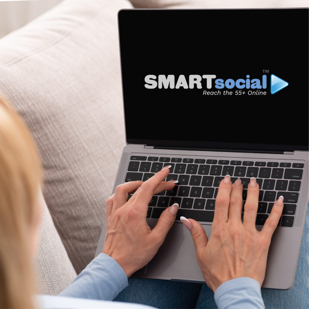OLDER WOMAN TYPING ON LAPTOP WITH SMARTSOCIAL ON SCREEN